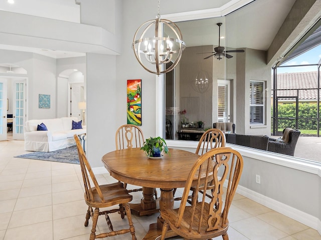 dining room with ceiling fan with notable chandelier, arched walkways, baseboards, and light tile patterned floors