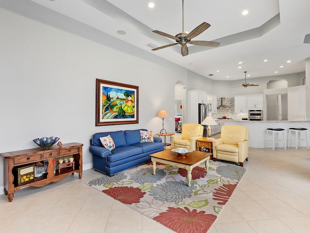 living room with light tile patterned floors, visible vents, arched walkways, ceiling fan, and recessed lighting