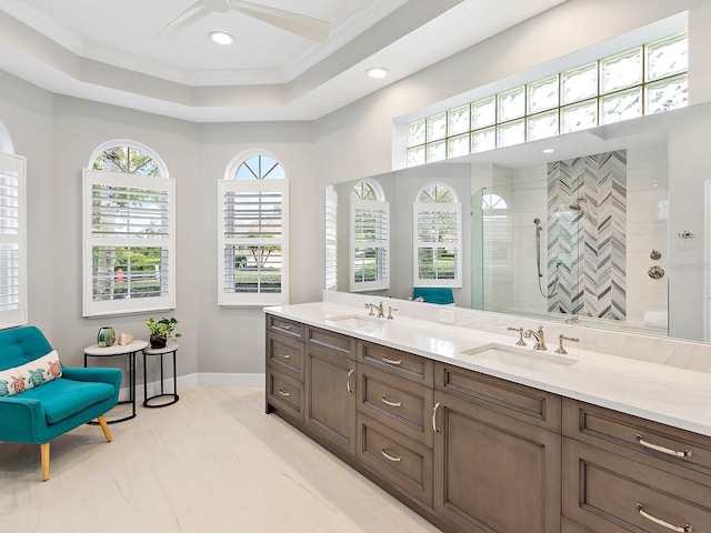 full bath with crown molding, a tray ceiling, tiled shower, and a sink