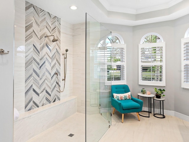 full bathroom featuring crown molding, a raised ceiling, a tile shower, and baseboards