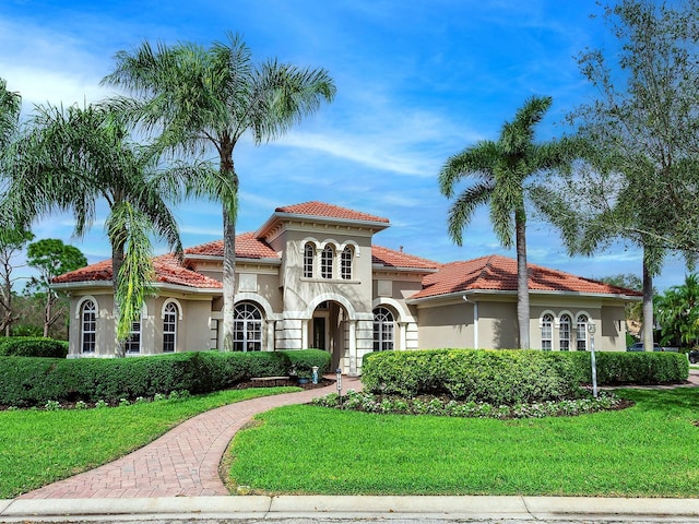 mediterranean / spanish-style home with stucco siding, a tile roof, and a front yard