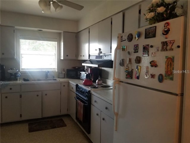 kitchen featuring black range with electric stovetop, a sink, white cabinetry, light countertops, and freestanding refrigerator