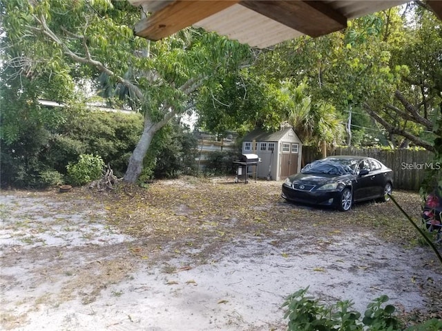 view of yard featuring an outbuilding, fence, and a shed