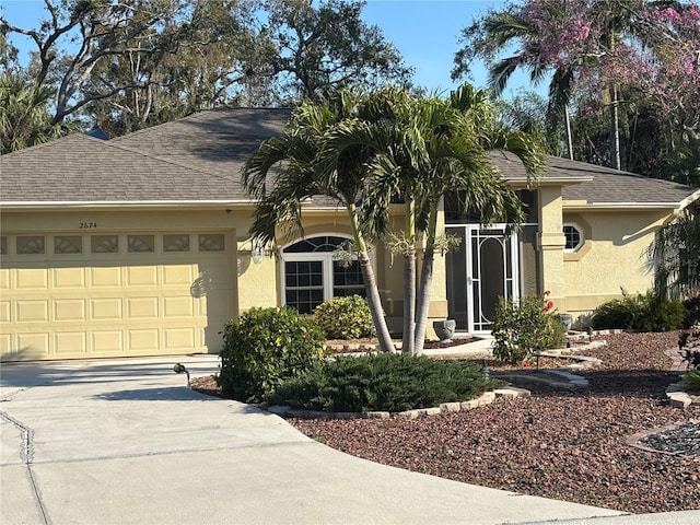 ranch-style home featuring a garage, concrete driveway, a shingled roof, and stucco siding