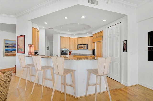 kitchen featuring stainless steel appliances, light wood-style flooring, a peninsula, and visible vents