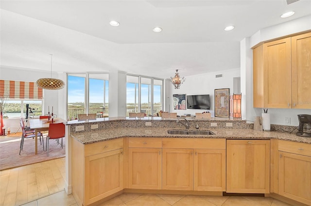 kitchen with light stone countertops, a sink, and light brown cabinetry