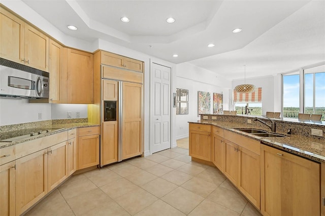 kitchen featuring stainless steel microwave, light brown cabinetry, a sink, paneled refrigerator, and black electric cooktop