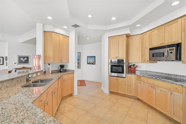 kitchen featuring stainless steel appliances, a raised ceiling, visible vents, light brown cabinetry, and a sink