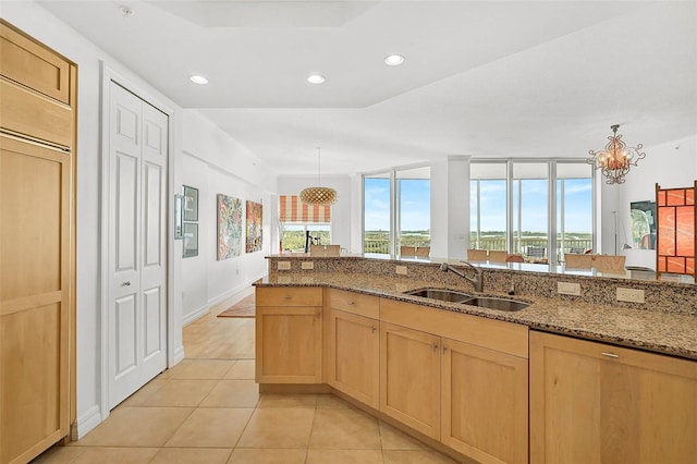 kitchen with stone countertops, light tile patterned flooring, light brown cabinetry, a sink, and recessed lighting