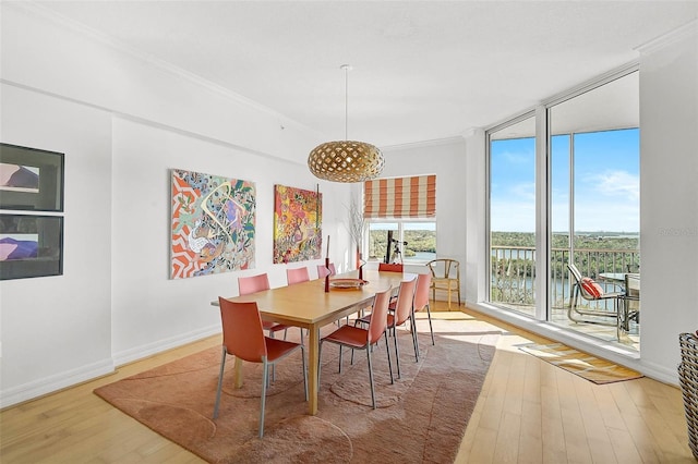 dining space featuring baseboards, expansive windows, ornamental molding, and wood finished floors