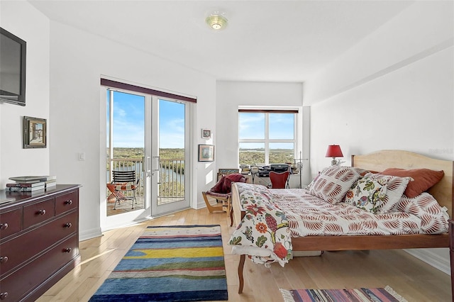 bedroom with access to outside, light wood-style flooring, and baseboards