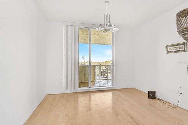 unfurnished dining area featuring a chandelier, baseboards, and light wood finished floors