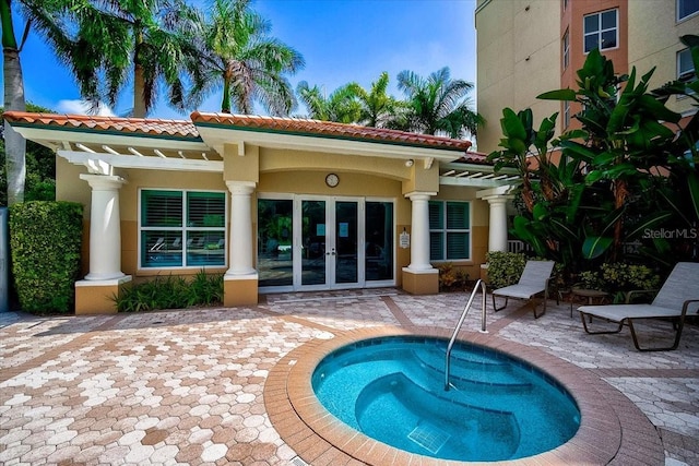 rear view of house with a patio, french doors, a tiled roof, and stucco siding