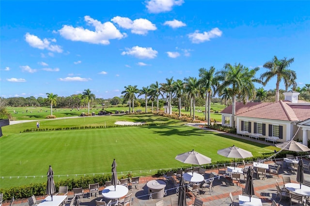 view of home's community featuring view of golf course, a patio, and a yard