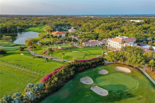 aerial view featuring view of golf course, a water view, and a wooded view