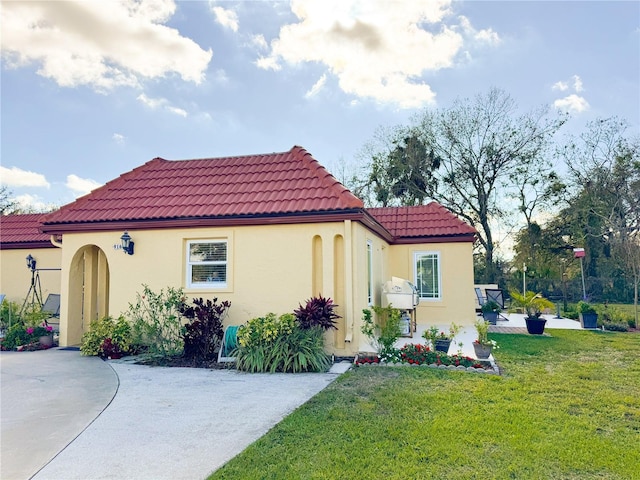 mediterranean / spanish-style house featuring a front yard, a tile roof, and stucco siding