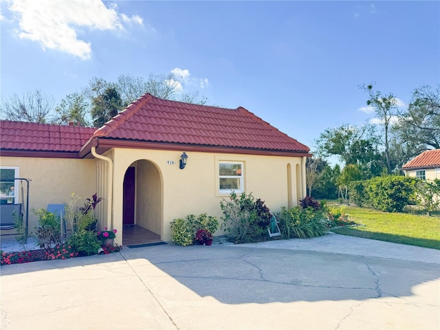 mediterranean / spanish house featuring a tile roof and stucco siding