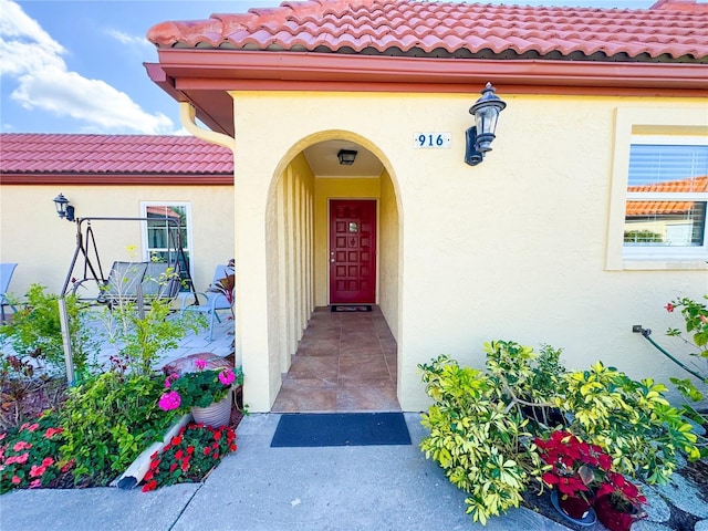 entrance to property with a tiled roof and stucco siding