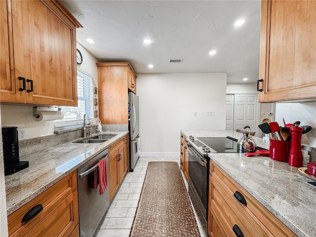 kitchen featuring appliances with stainless steel finishes, visible vents, a sink, and light stone counters