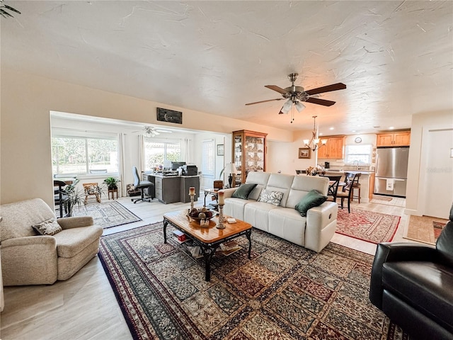 living area featuring ceiling fan with notable chandelier and light wood finished floors