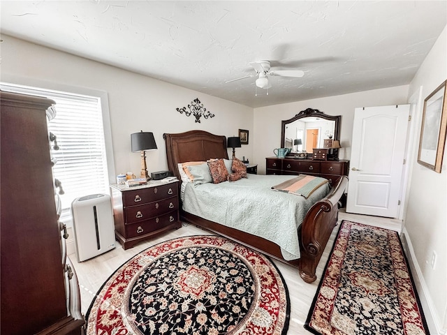 bedroom with ceiling fan, light wood-style floors, and baseboards