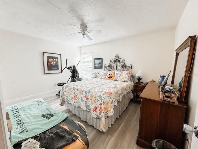 bedroom with a ceiling fan, light wood-type flooring, a textured ceiling, and baseboards