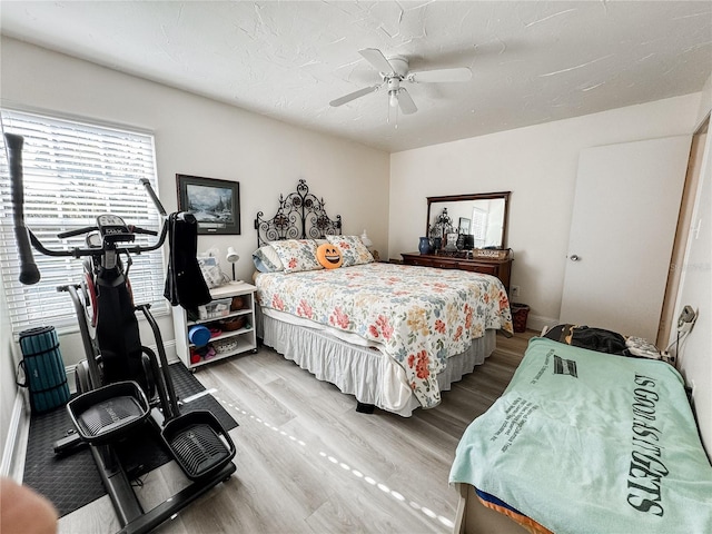 bedroom featuring light wood finished floors, a ceiling fan, and baseboards