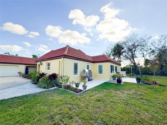 back of house featuring an attached garage, a tile roof, a yard, concrete driveway, and stucco siding