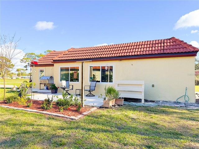 back of property with a patio, a yard, and stucco siding