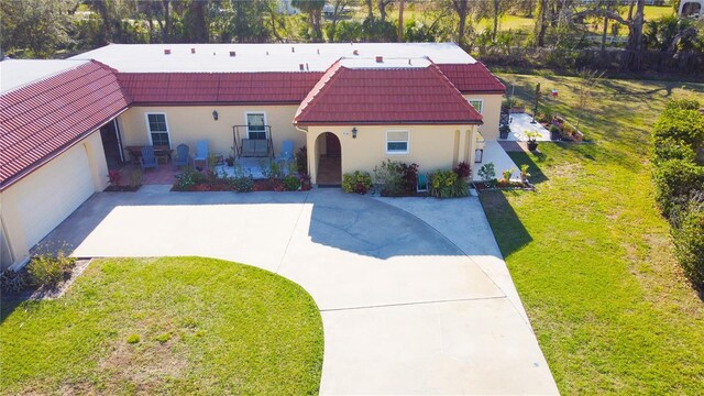 mediterranean / spanish-style house featuring a tile roof, concrete driveway, and a front yard