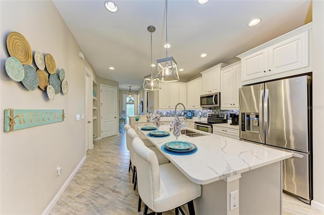 11607 Meadowgate Pl, Bradenton, FL 34211 - kitchen with a center island with sink, a breakfast bar, recessed lighting, white cabinets, and appliances with stainless steel finishes