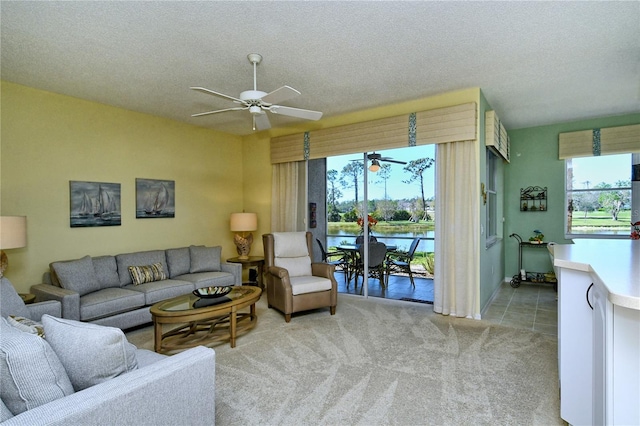 living area with a ceiling fan, light carpet, and a textured ceiling