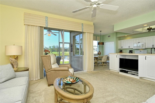 living room featuring visible vents, light colored carpet, ceiling fan, and a textured ceiling