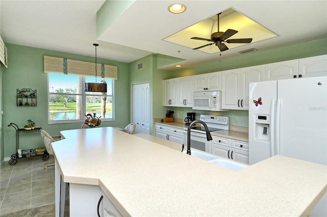 kitchen with white appliances, a sink, white cabinets, light countertops, and hanging light fixtures