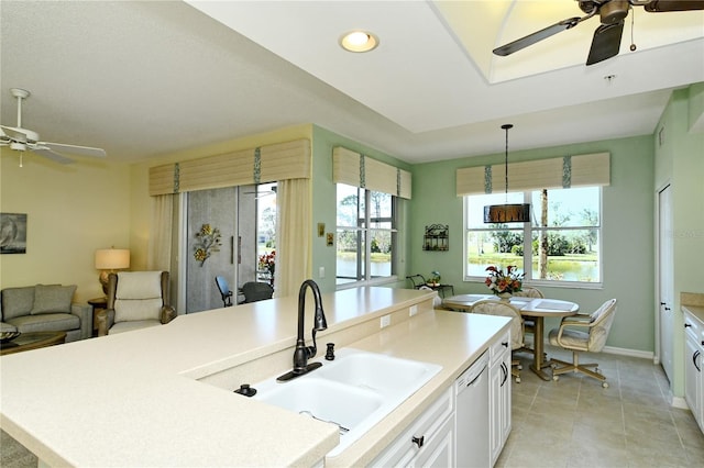 kitchen featuring light countertops, open floor plan, white cabinetry, a sink, and dishwasher