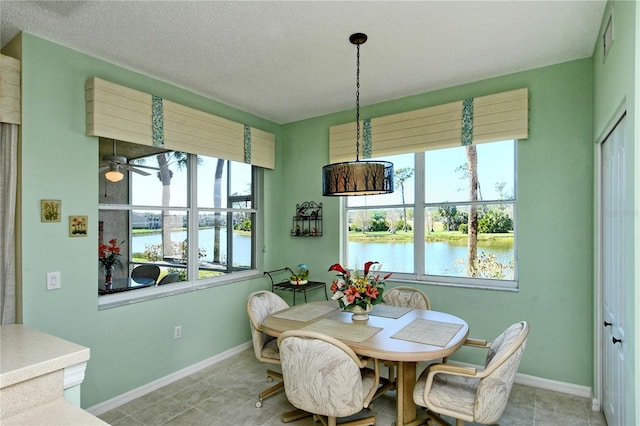 dining room featuring a water view, ceiling fan, and baseboards