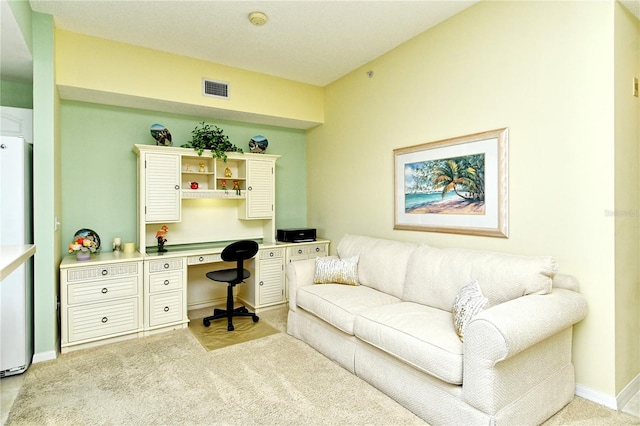 office space with baseboards, built in desk, visible vents, and light colored carpet