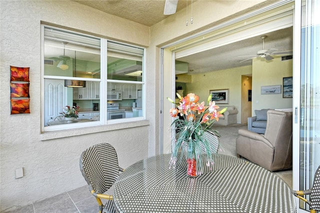 dining space with a ceiling fan and a textured wall