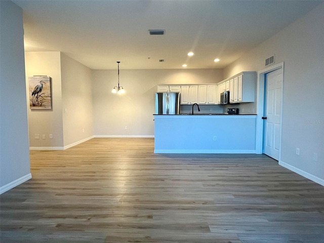 kitchen featuring visible vents, appliances with stainless steel finishes, decorative light fixtures, light wood-type flooring, and white cabinetry