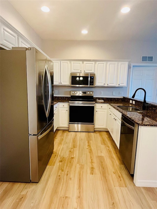 kitchen with light wood-style flooring, stainless steel appliances, a sink, visible vents, and white cabinetry