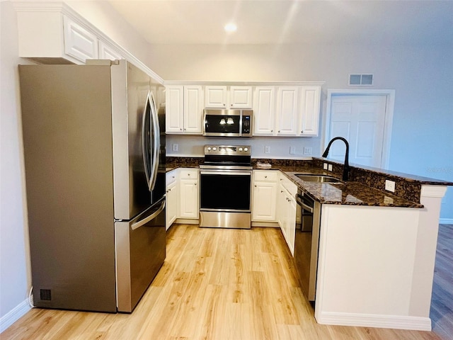 kitchen with a peninsula, visible vents, white cabinetry, and stainless steel appliances