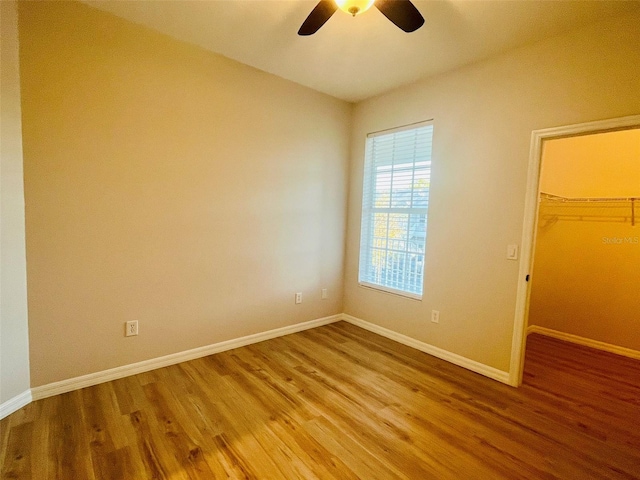 spare room featuring ceiling fan, baseboards, and wood finished floors