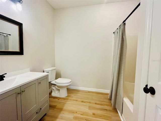 bathroom with toilet, shower / bath combo, vanity, wood finished floors, and baseboards