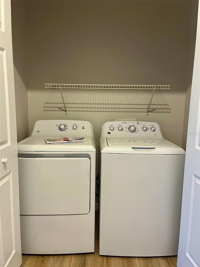 washroom with light wood-style flooring, laundry area, and washer and clothes dryer