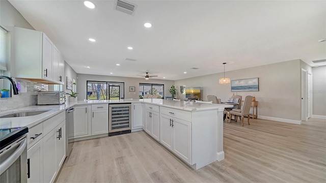 kitchen featuring light wood finished floors, wine cooler, appliances with stainless steel finishes, and a sink