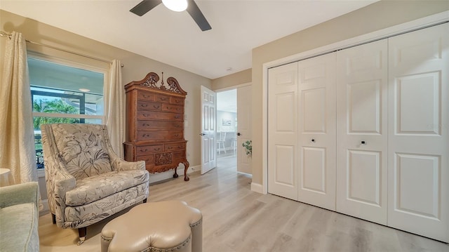 living area with light wood-style floors, baseboards, and a ceiling fan