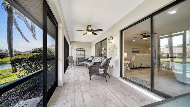 sunroom / solarium featuring a ceiling fan and a water view