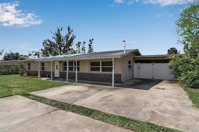 ranch-style home featuring stucco siding, a gate, a front lawn, and brick siding