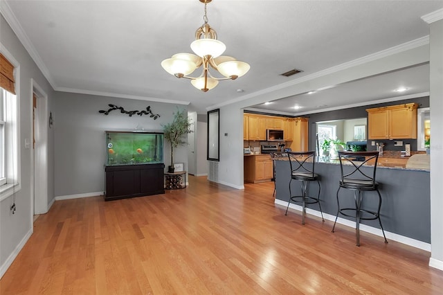 kitchen featuring light wood-type flooring, stainless steel microwave, crown molding, and a kitchen breakfast bar