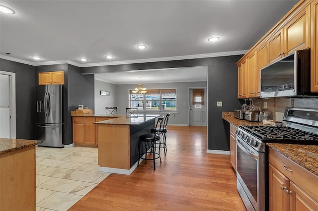 kitchen featuring a breakfast bar, marble finish floor, appliances with stainless steel finishes, a center island, and dark stone countertops